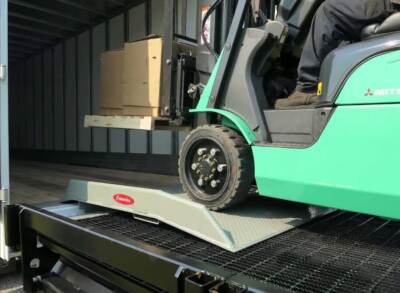 a close shot of a forklift removing stock from a truck using a loading ramp
